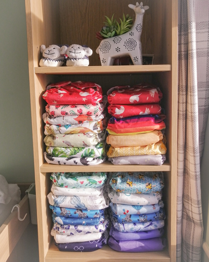 Colourful cloth nappies stacked on shelves in nursery bedroom